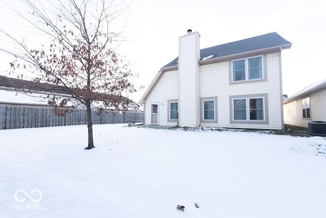 snow covered rear of property featuring central AC unit