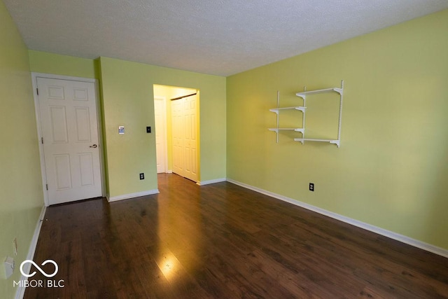 spare room featuring dark hardwood / wood-style floors and a textured ceiling