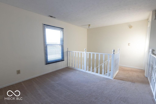 carpeted empty room featuring a textured ceiling