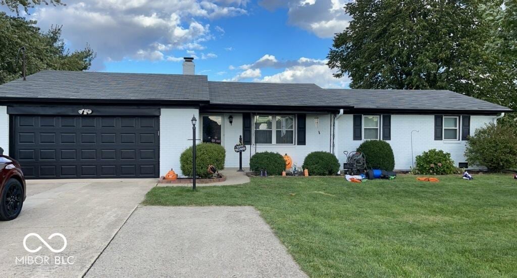 ranch-style home featuring a garage and a front lawn