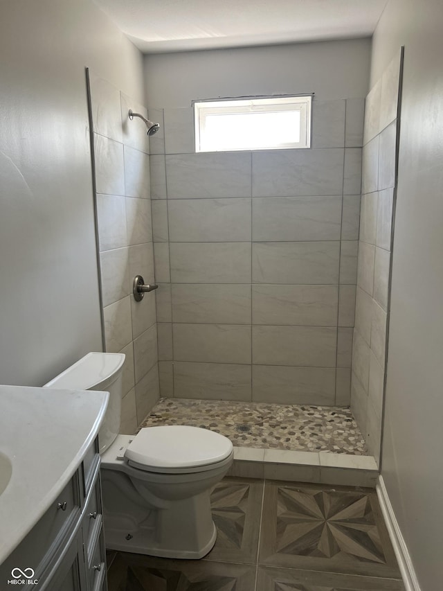 bathroom featuring tiled shower, vanity, and toilet