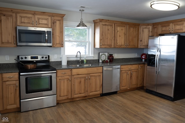 kitchen with decorative light fixtures, sink, appliances with stainless steel finishes, and dark hardwood / wood-style floors