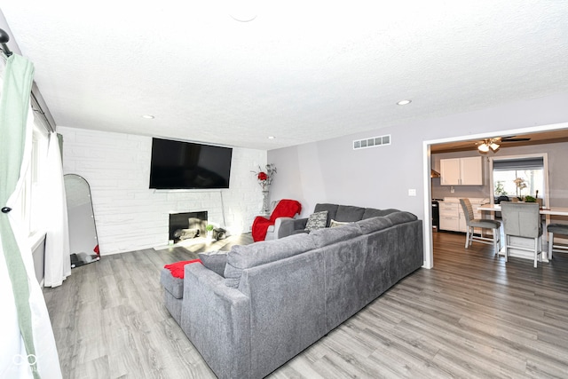 living room with a fireplace, a textured ceiling, and light hardwood / wood-style flooring