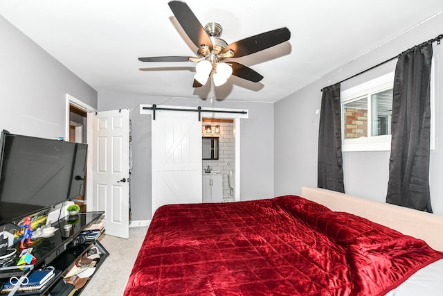 carpeted bedroom with connected bathroom, a barn door, and ceiling fan