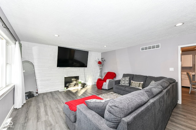 living room with a fireplace, wood-type flooring, and a textured ceiling