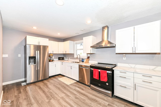 kitchen with white cabinetry, wall chimney range hood, stainless steel appliances, and sink