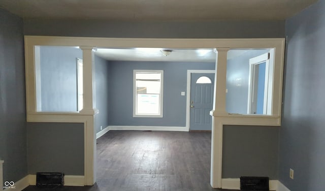 foyer entrance with dark wood-type flooring and decorative columns