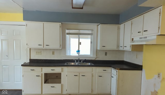 kitchen with backsplash, white cabinets, and sink