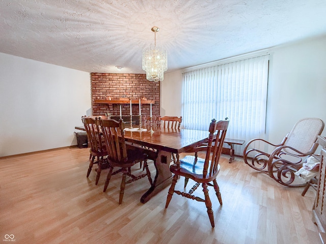 dining space with light wood-type flooring, an inviting chandelier, and a textured ceiling