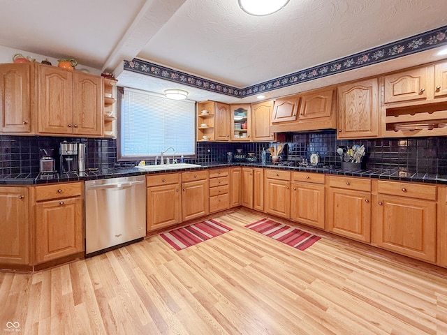 kitchen featuring stainless steel dishwasher, sink, light wood-type flooring, beam ceiling, and a textured ceiling