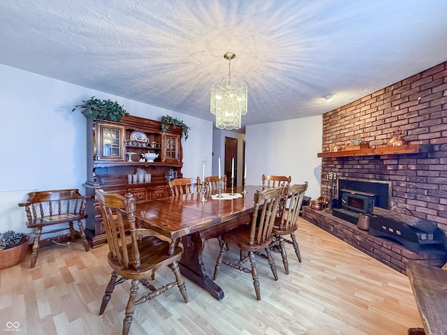 dining room with light hardwood / wood-style floors, a textured ceiling, and an inviting chandelier