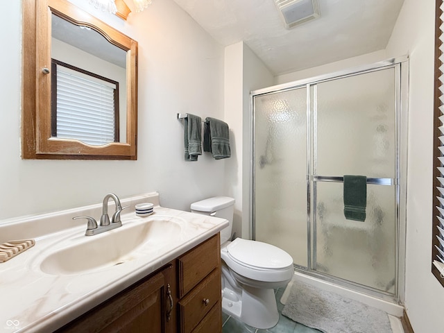 bathroom featuring a shower with shower door, toilet, vanity, and tile patterned flooring