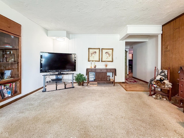 carpeted living room with a textured ceiling, wooden walls, and ornamental molding