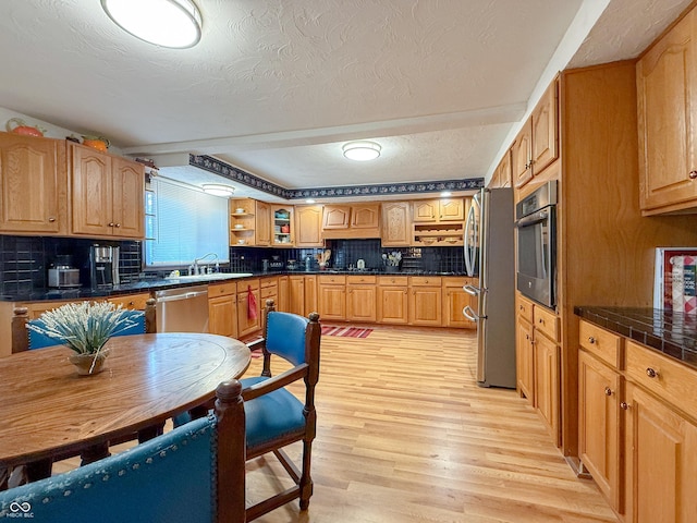 kitchen with light hardwood / wood-style floors, sink, backsplash, and appliances with stainless steel finishes