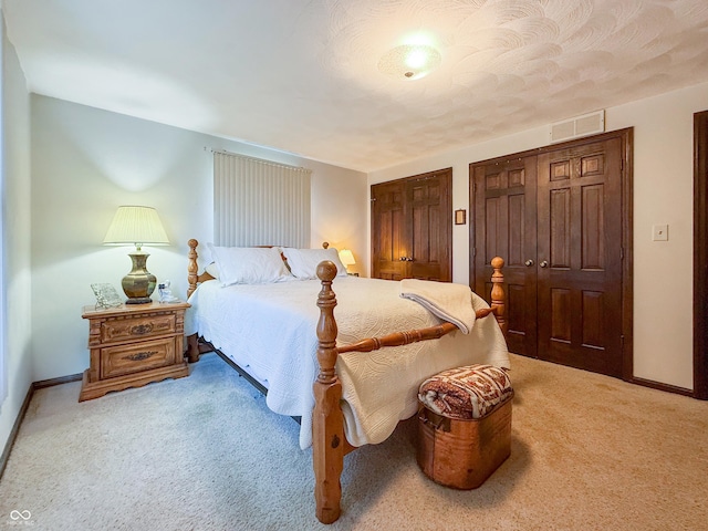 carpeted bedroom featuring multiple closets and a textured ceiling