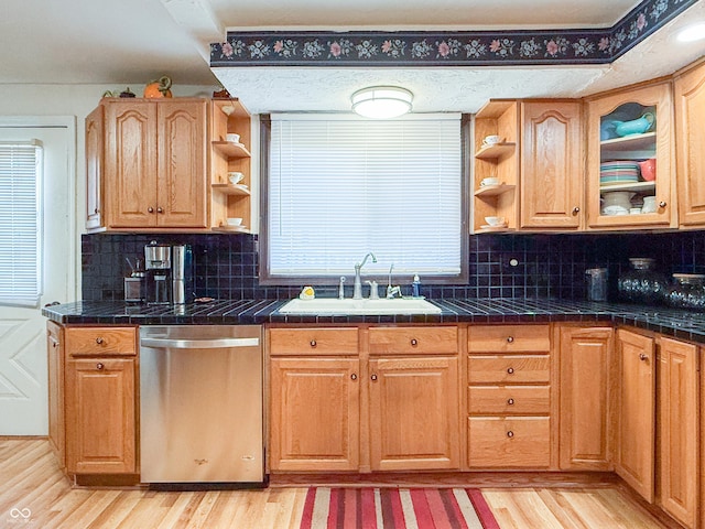 kitchen with tile counters, dishwasher, sink, light hardwood / wood-style flooring, and backsplash