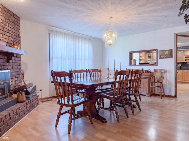 dining space featuring a textured ceiling, light hardwood / wood-style flooring, and a notable chandelier