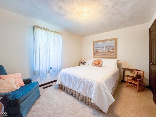 bedroom featuring light carpet and a textured ceiling