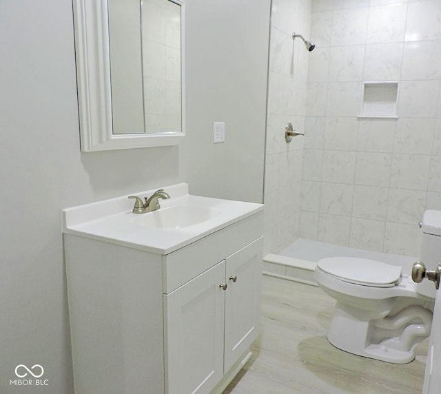 bathroom with vanity, tiled shower, and toilet