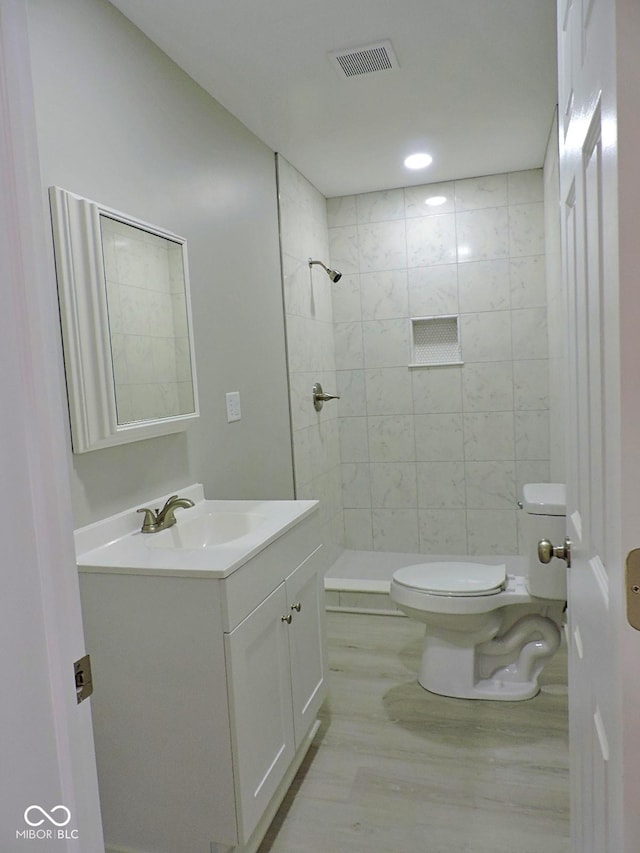 bathroom with vanity, toilet, and a tile shower