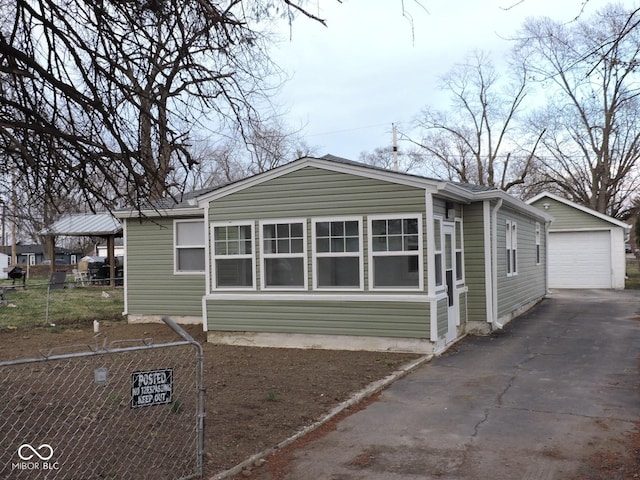 exterior space with an outdoor structure, a detached garage, fence, and driveway