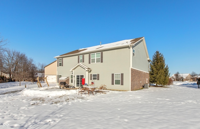 snow covered rear of property with cooling unit