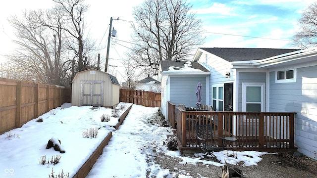 snowy yard with a wooden deck and a storage unit