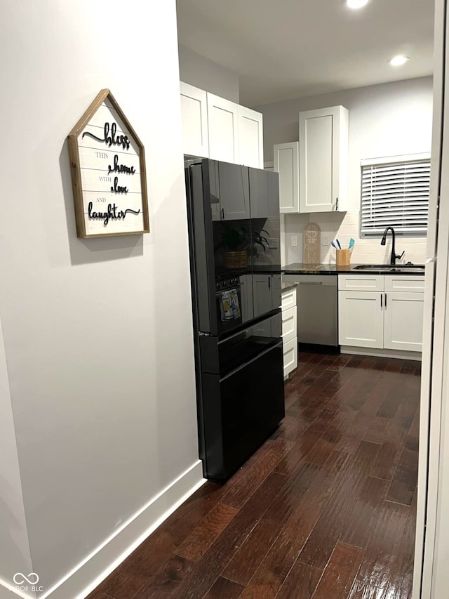 kitchen featuring dark wood-type flooring, dishwasher, sink, and white cabinetry