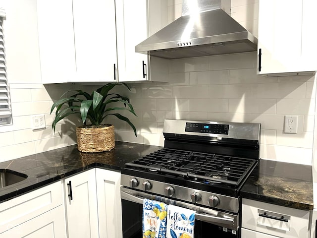 kitchen with backsplash, stainless steel gas range oven, extractor fan, and white cabinetry