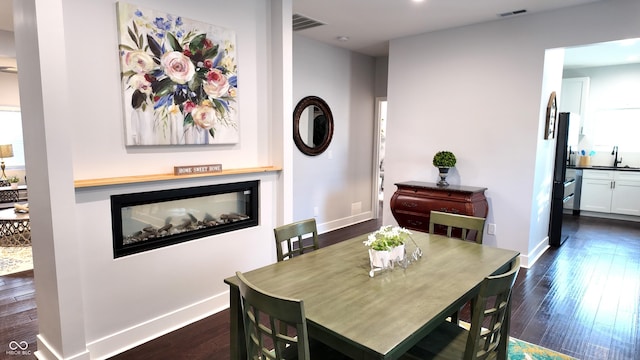 dining area featuring a multi sided fireplace, dark hardwood / wood-style floors, and sink