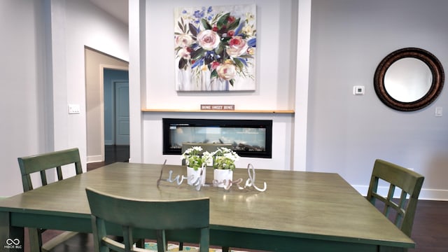 dining room with dark hardwood / wood-style flooring and a multi sided fireplace