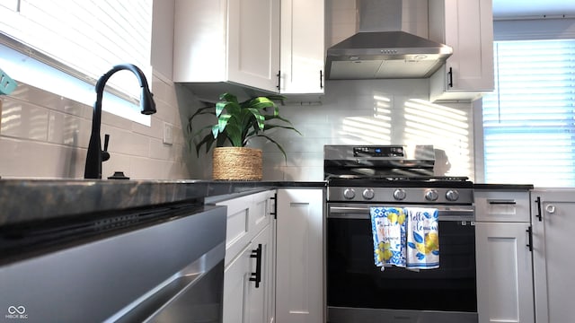 kitchen with appliances with stainless steel finishes, wall chimney exhaust hood, decorative backsplash, and white cabinetry