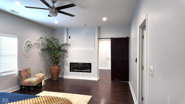 bedroom with ceiling fan, dark hardwood / wood-style flooring, a barn door, and multiple windows