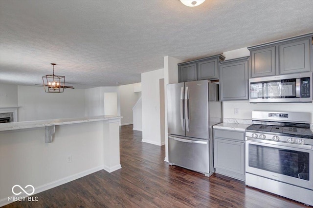 kitchen featuring dark wood-type flooring, gray cabinets, stainless steel appliances, and a kitchen bar