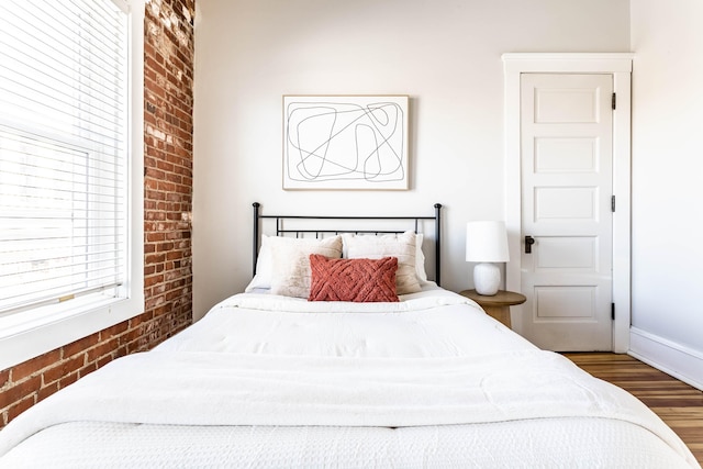 bedroom featuring brick wall and hardwood / wood-style floors