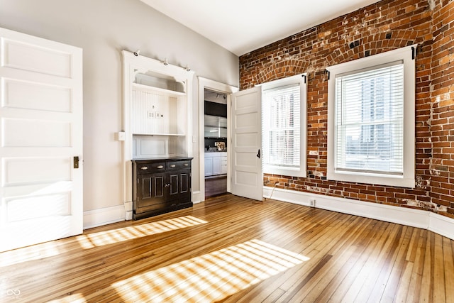 interior space with brick wall and hardwood / wood-style flooring