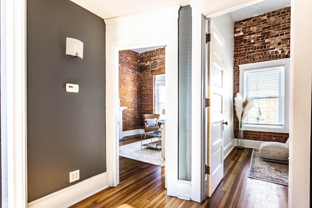 hall with brick wall and hardwood / wood-style flooring