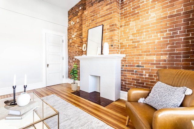 living room featuring hardwood / wood-style flooring and brick wall