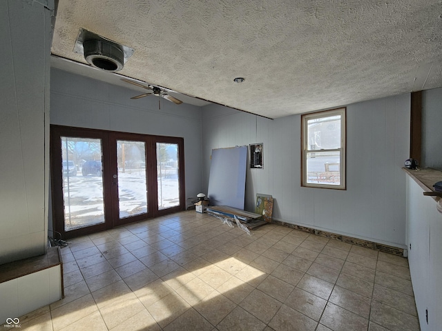 unfurnished living room featuring ceiling fan, a textured ceiling, french doors, and light tile patterned flooring