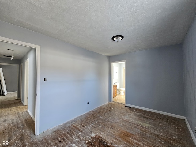 unfurnished room featuring dark wood-type flooring and a textured ceiling