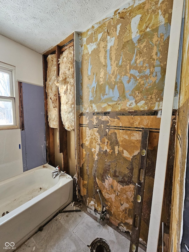 bathroom with a tub and a textured ceiling