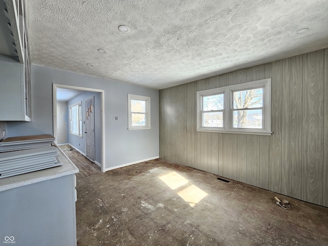 interior space featuring a textured ceiling, wood walls, and a healthy amount of sunlight