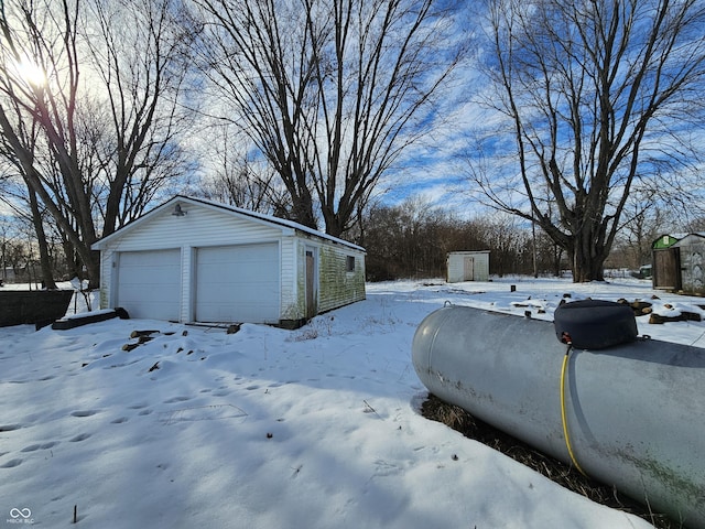 view of snowy exterior with a garage and an outbuilding