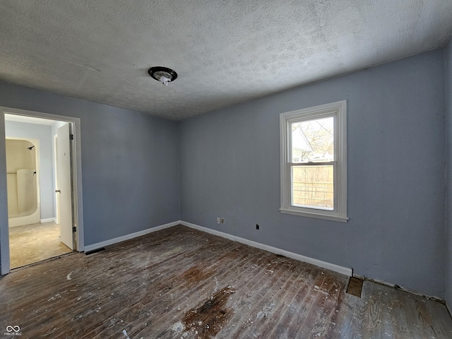 spare room featuring a textured ceiling and dark wood-type flooring