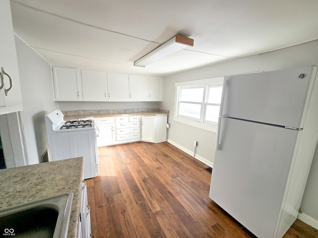 kitchen with dark wood-type flooring, sink, white appliances, and white cabinetry