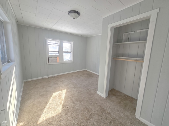 unfurnished bedroom featuring cooling unit, a closet, and light carpet