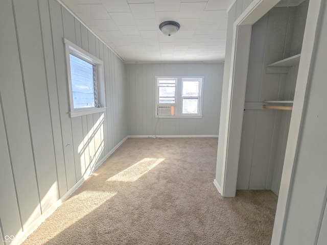 interior space featuring light colored carpet, cooling unit, and wood walls