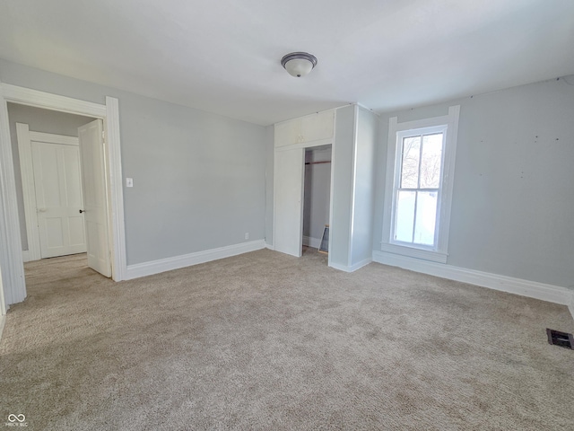 unfurnished bedroom with light colored carpet and a closet