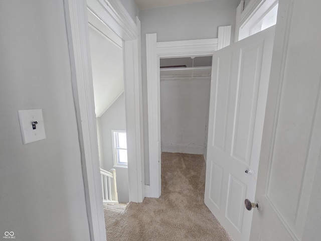 corridor featuring light colored carpet and vaulted ceiling