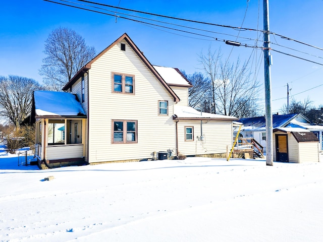 snow covered property featuring a storage shed and a porch